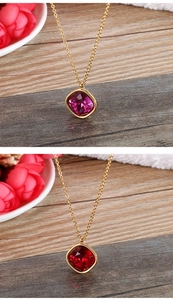 Detailweergave van de vierkante rozerode en donkerrode edelsteen hangers aan goudketting
