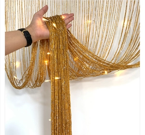 Close-up of golden flat silk door curtain with warm white LED string lights
