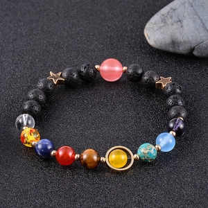 Bracelet système solaire avec perles en pierre de lave et planètes sur fond de sable