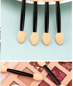 Close-up of double-sided sponge eyeshadow applicators and usage on a makeup palette