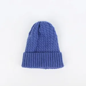 Detailansicht des dicken blauen Zopfmusters einer winterlichen Strickmütze aus Wolle