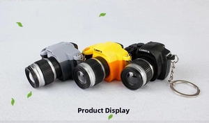 Macro detail of mini SLR camera keychains in grey, yellow and black with realistic buttons