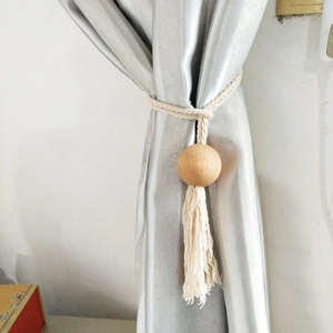 Close-up of cotton rope curtain tieback with decorative round wooden bead and tassel