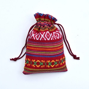 Macro view of red ethnic drawstring pouch with colorful woven geometric patterns