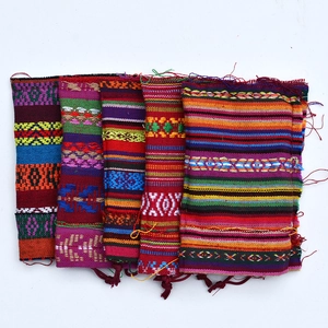 Close-up of ethnic cotton drawstring pouches with vibrant colorful stripes and tassels