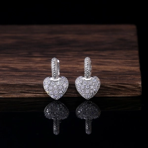 Macro shot of silver heart drop earrings with shimmering zircon pavé on dark background