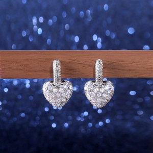 Detail of silver heart earrings with pavé set cubic zirconia on a wooden stand