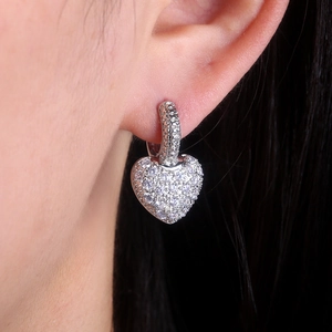 Sparkling zircon heart drop earrings in silver finish worn by a model in natural light