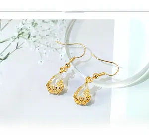 Macro shot of French style waterdrop crystal earrings with golden floral hollow base