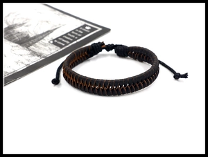 Detail of hand-woven dark brown leather cord bracelet with adjustable closure on white background