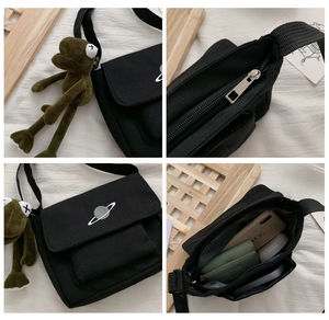 Detail view of black canvas crossbody bag with star embroidery and frog plush charm