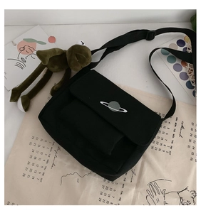 Detailed view of black canvas crossbody bag featuring a planet embroidery on the flap cover