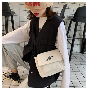 Detail of white canvas crossbody bag with planet embroidery and black adjustable strap