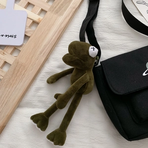 Japanese style green long-limbed frog plush keychain attached to large black canvas bag