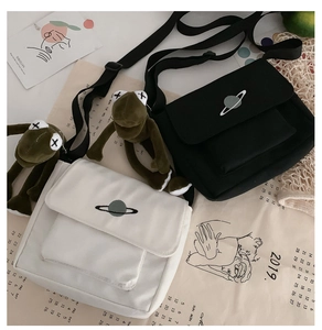 Detailed close-up of canvas crossbody bags in black and white with planet embroidery