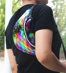Close-up of rainbow sequin fanny pack with black adjustable strap worn by model