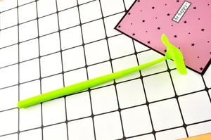 Close-up of green silicone clover gel pen with creative leaf topper on a grid mat