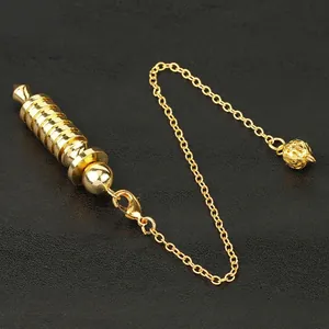 Golden spiral metal pendulum with chain and hollow orb on a textured black background