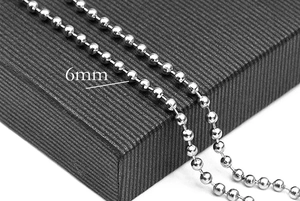 Macro detail of 6mm stainless steel ball chain jewelry on a black textured display box