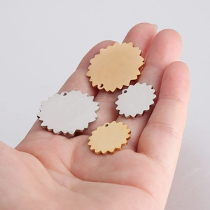 Polished flower-shaped stainless steel charms in gold and silver held by a hand