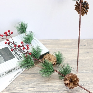 Christmas pine branch with red berries and pinecones on white wooden surface
