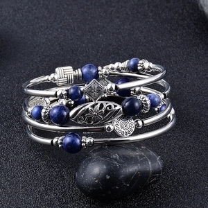 Detailansicht des mehrlagigen Wickelarmbands mit silbernem Metall und blauen Steinen.