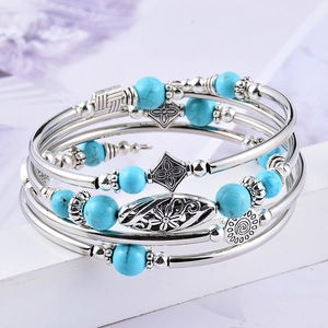 Macro shot of layered turquoise beads and silver carved metal charms on a multi-wrap bracelet
