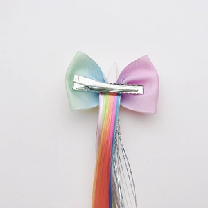 Close-up of rainbow wig hair extension with pink bow on a metal alligator clip for girls