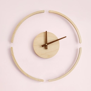 Minimalist wooden wall clock with floating ring design on light pink wall background