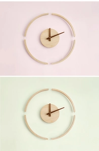 Minimalist wooden wall clock with dark wood hands shown against pastel backdrops