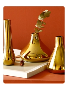 Detailed view of three modern gold ceramic vases set with metallic electroplated finish