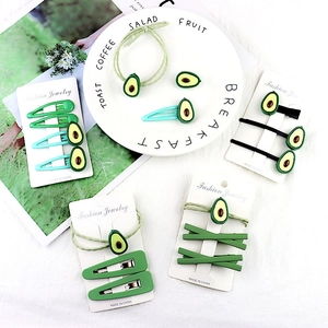Flat lay of avocado themed hair clip and scrunchie set on a white decorative plate