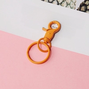 Close-up of orange painted metal lobster clasp keyring on decorative card background