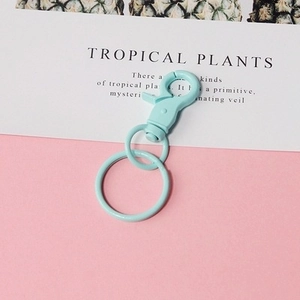 Detail of light blue swivel lobster clasp with metal rings on minimalist pink background