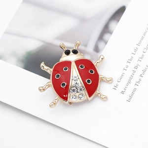 Detailed close-up of a ladybug brooch with red enamel wings and crystal inlay
