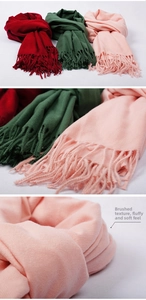 Detailed view of tasseled cashmere-like scarves in wine red, dark green and light pink