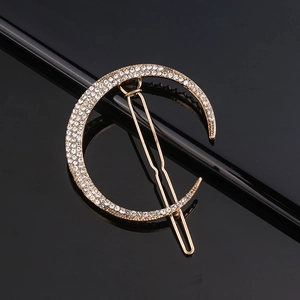 Golden moon-shaped hair clip with sparkling rhinestones on a black background