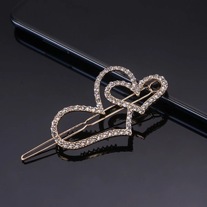 Elegant gold double heart hair clip with sparkling rhinestones on dark mirror reflection