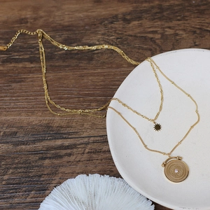 Detail of double-layer vintage gold necklace featuring a sunburst pendant and star charm