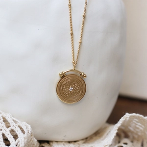 Macro shot of vintage gold satellite chain with star engraved coin pendant and zircon