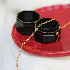 Macro shot of a golden water wave chain necklace in an elegant black octagonal jewelry box