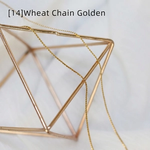 Detailed view of a gold wheat chain necklace featuring fine metal weaving on a stand