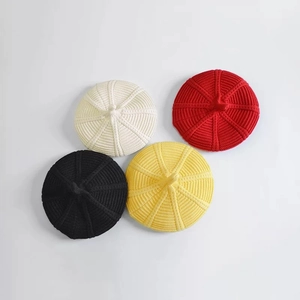 Kids knitted wool beret caps in white, red, black and yellow showing top texture