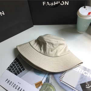 Close-up of beige wide-brim cotton bucket hat on fashion magazine with coffee cup