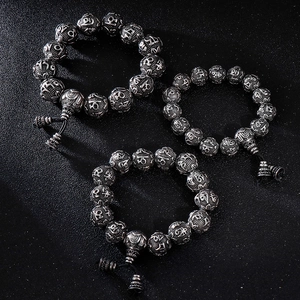 Vintage stainless steel braided bracelet with silver mantra beads on black texture