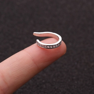 Macro shot of a silver U-shaped ear cuff with cubic zirconia on a fingertip