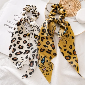 Detailed view of beige and yellow leopard print silk hair scrunchies with long ribbons