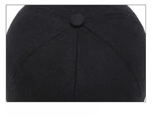 Detailed close-up of the six-panel crown stitching and top button on a black wool cap