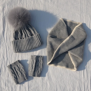 Close-up of three-piece knit set including fox pompom hat, scarf and fingerless gloves