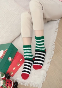 Thick warm coral fleece Christmas socks with festive red and green stripes on a model